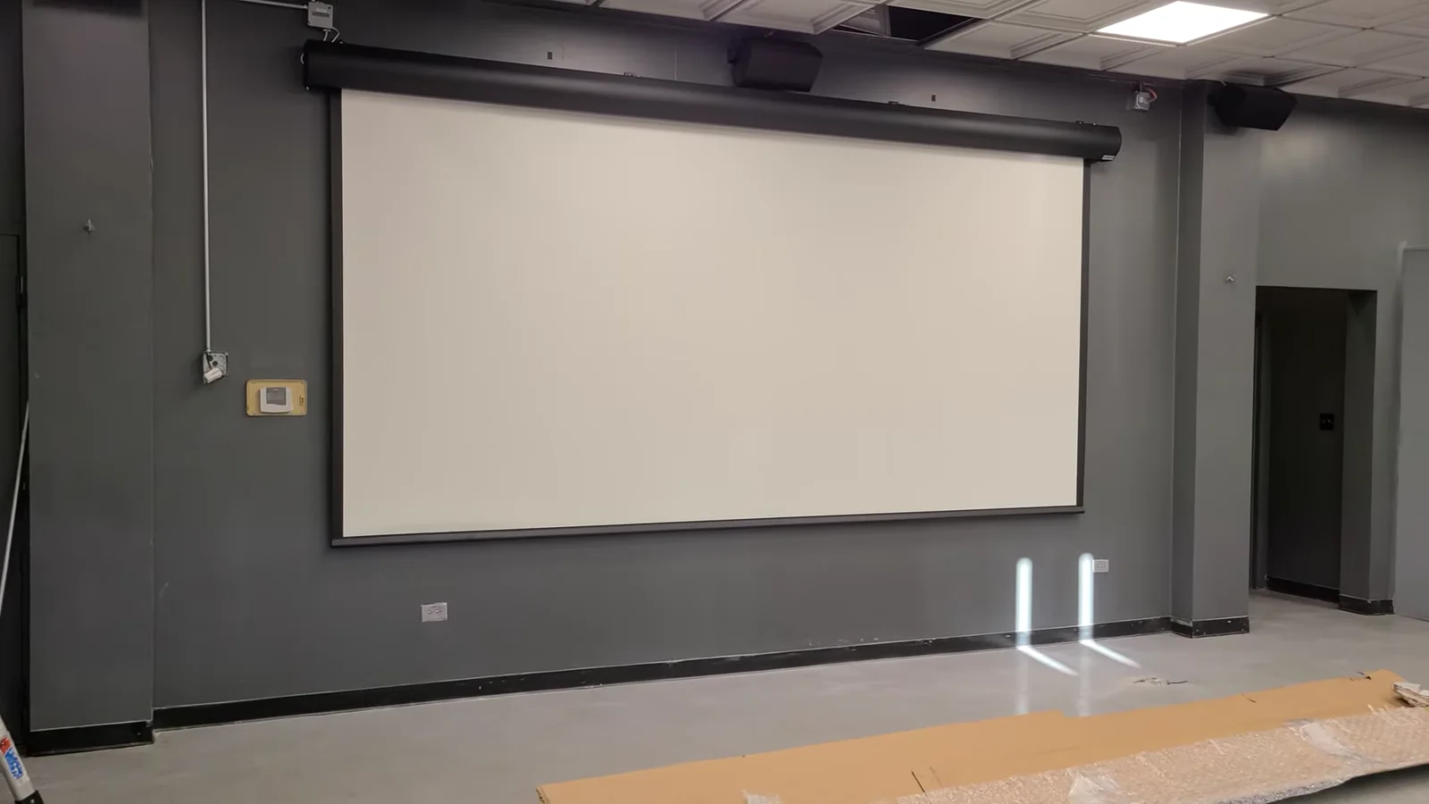 Fully deployed 190-inch motorized projection screen on a dark wall