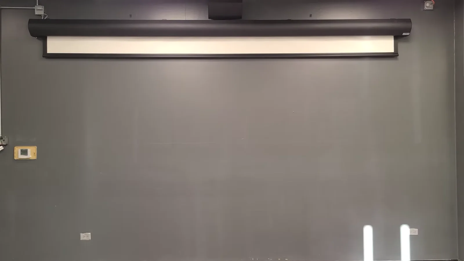 Large motorized projection screen retracted into its wall-mounted enclosure