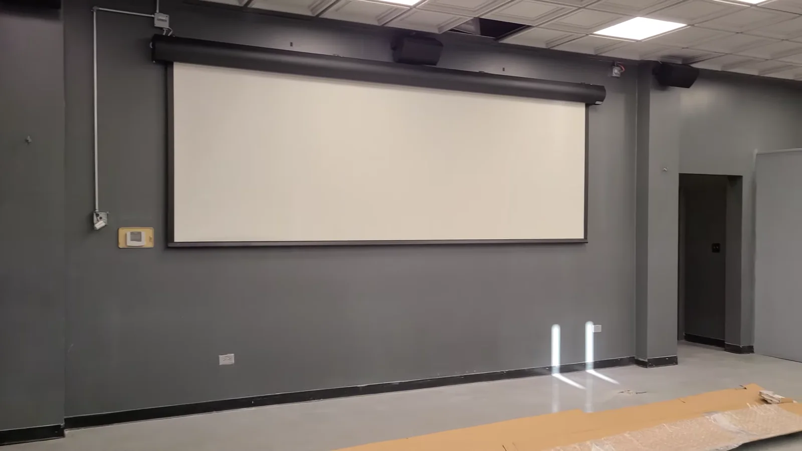 Motorized projection screen partially raised during travel testing