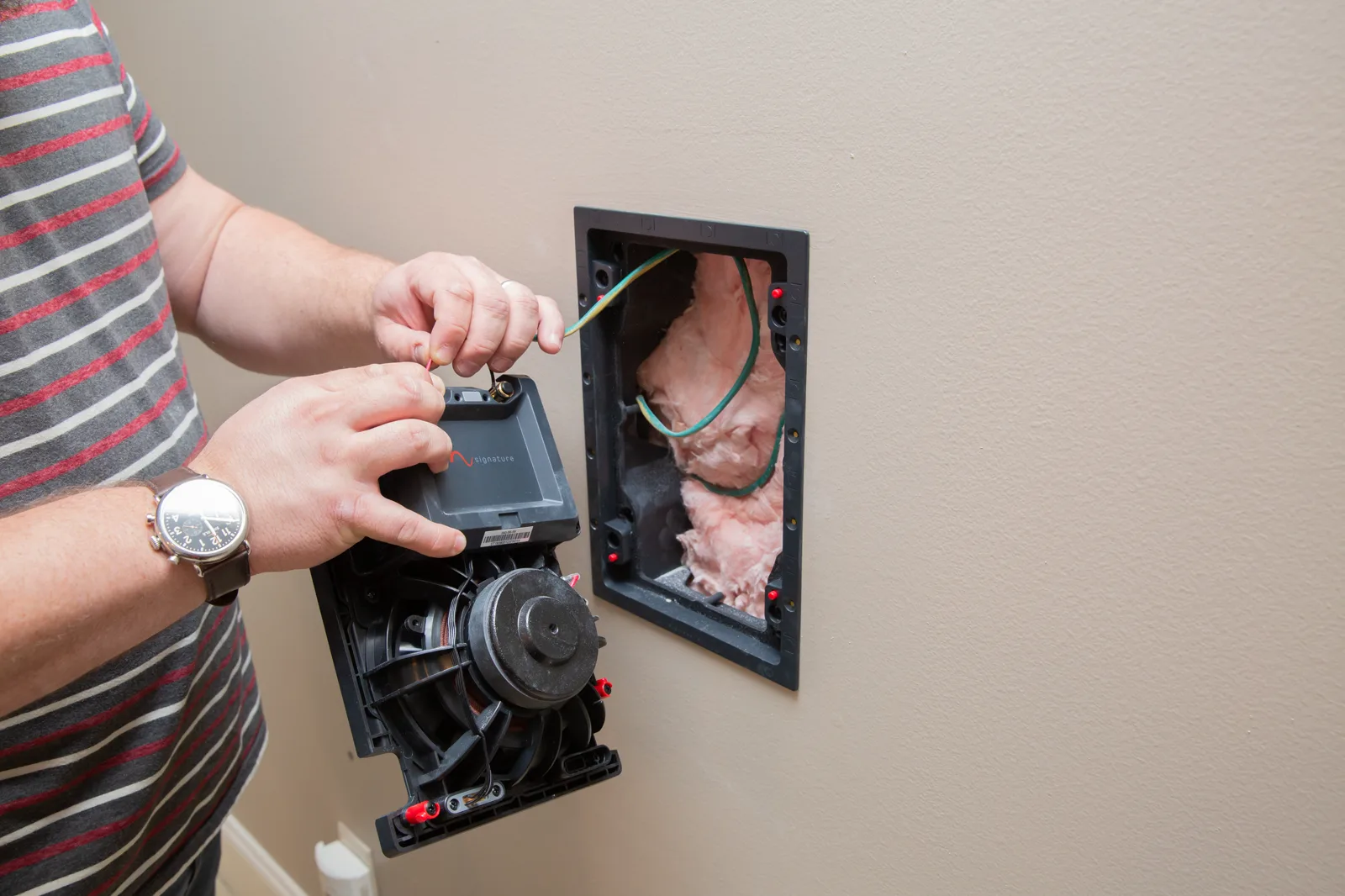 Installer connecting a Signature by Episode in-wall speaker to a prepared wall opening
