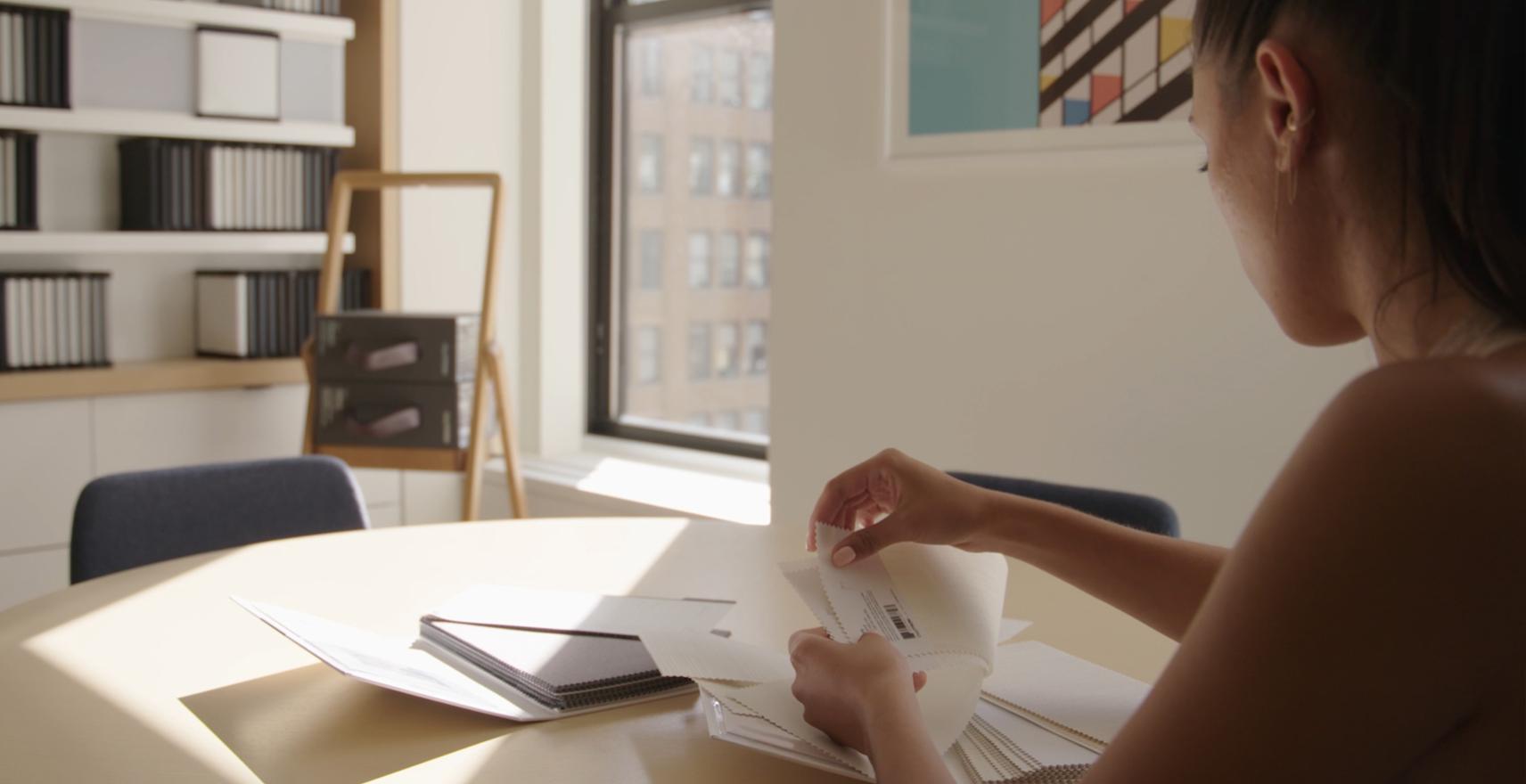 Designer reviewing motorized shade fabric samples beside a window