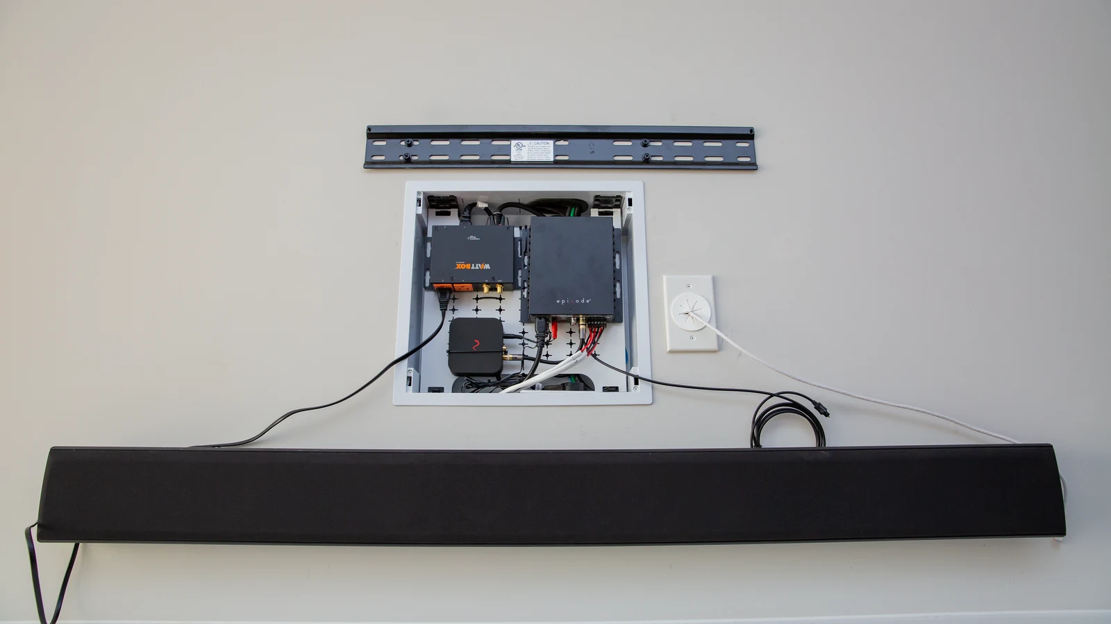 Strong television wall mount above a recessed equipment box and soundbar during installation
