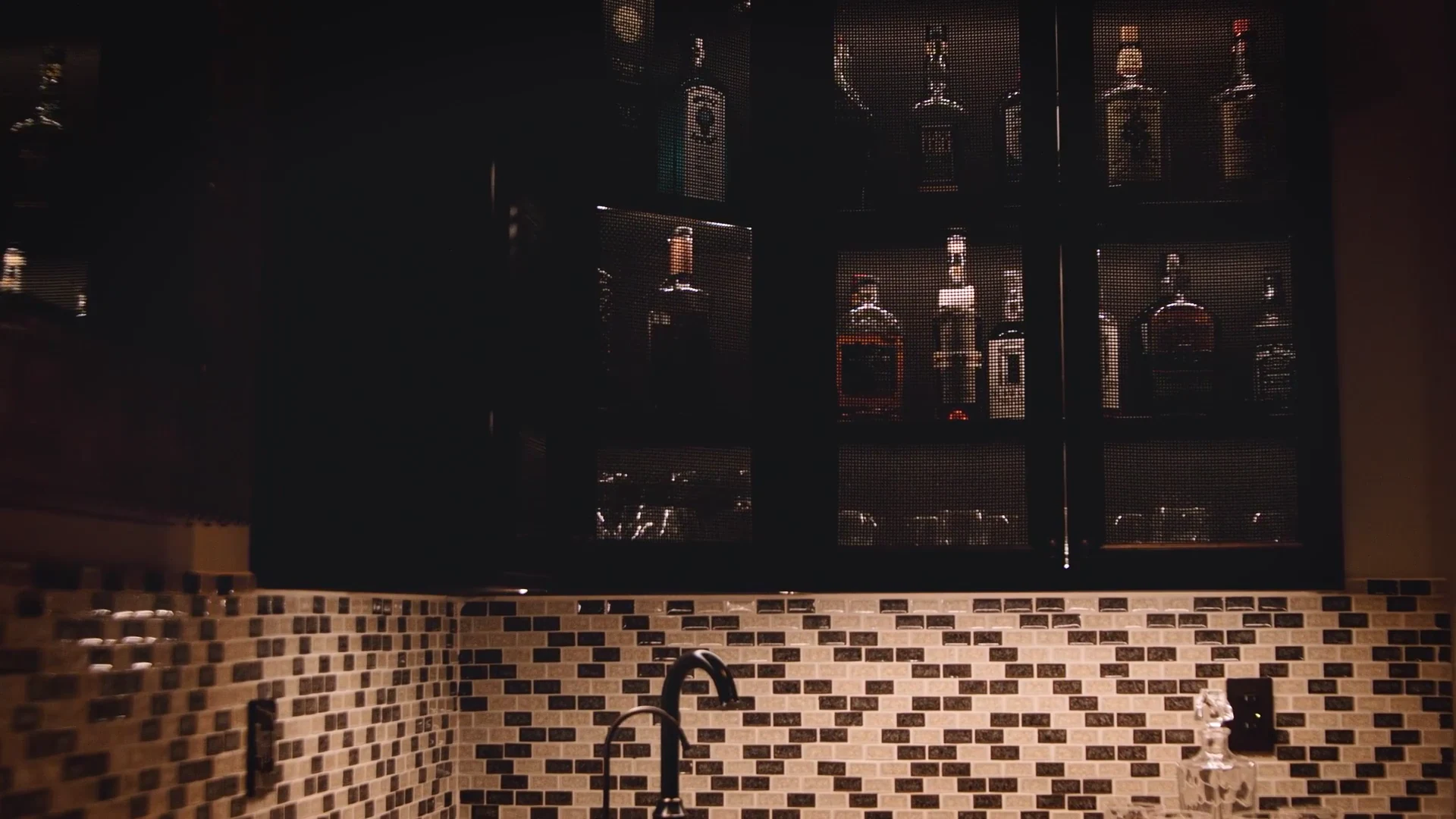 Warm linear lighting illuminating a bar backsplash and display cabinet