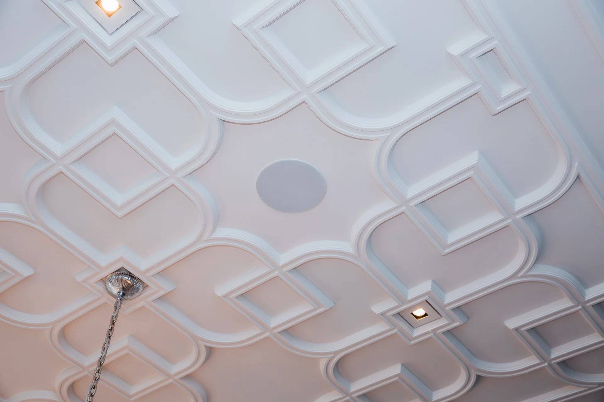Round in-ceiling speaker blended into a decorative ceiling