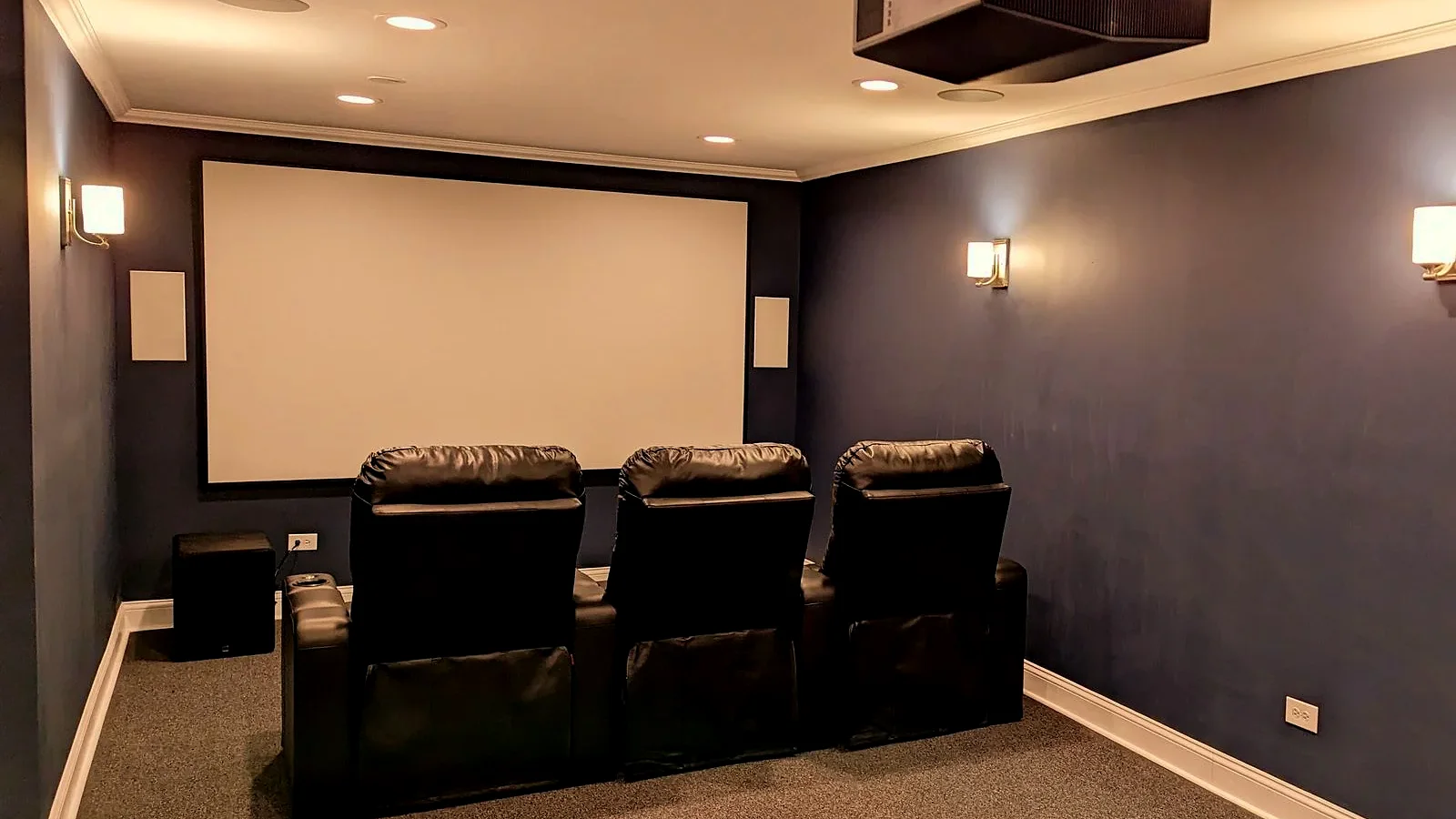 Dedicated home theater with projector, large screen, in-wall speakers, and theater seating