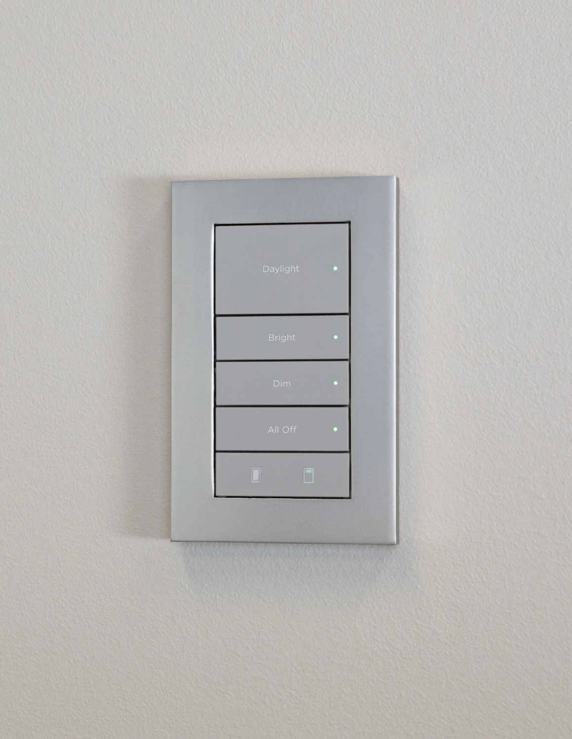 Complete light metallic Lux keypad and faceplate with engraved lighting labels on a pale wall