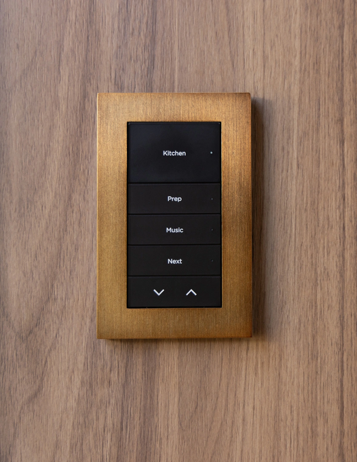 Complete Lux keypad with dark engraved buttons and a warm metallic faceplate on wood