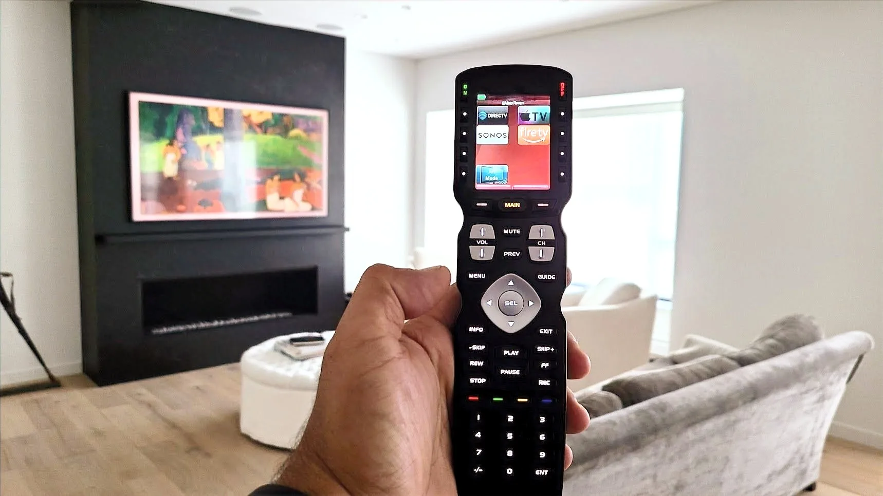 URC MX-990 remote held in a finished living room